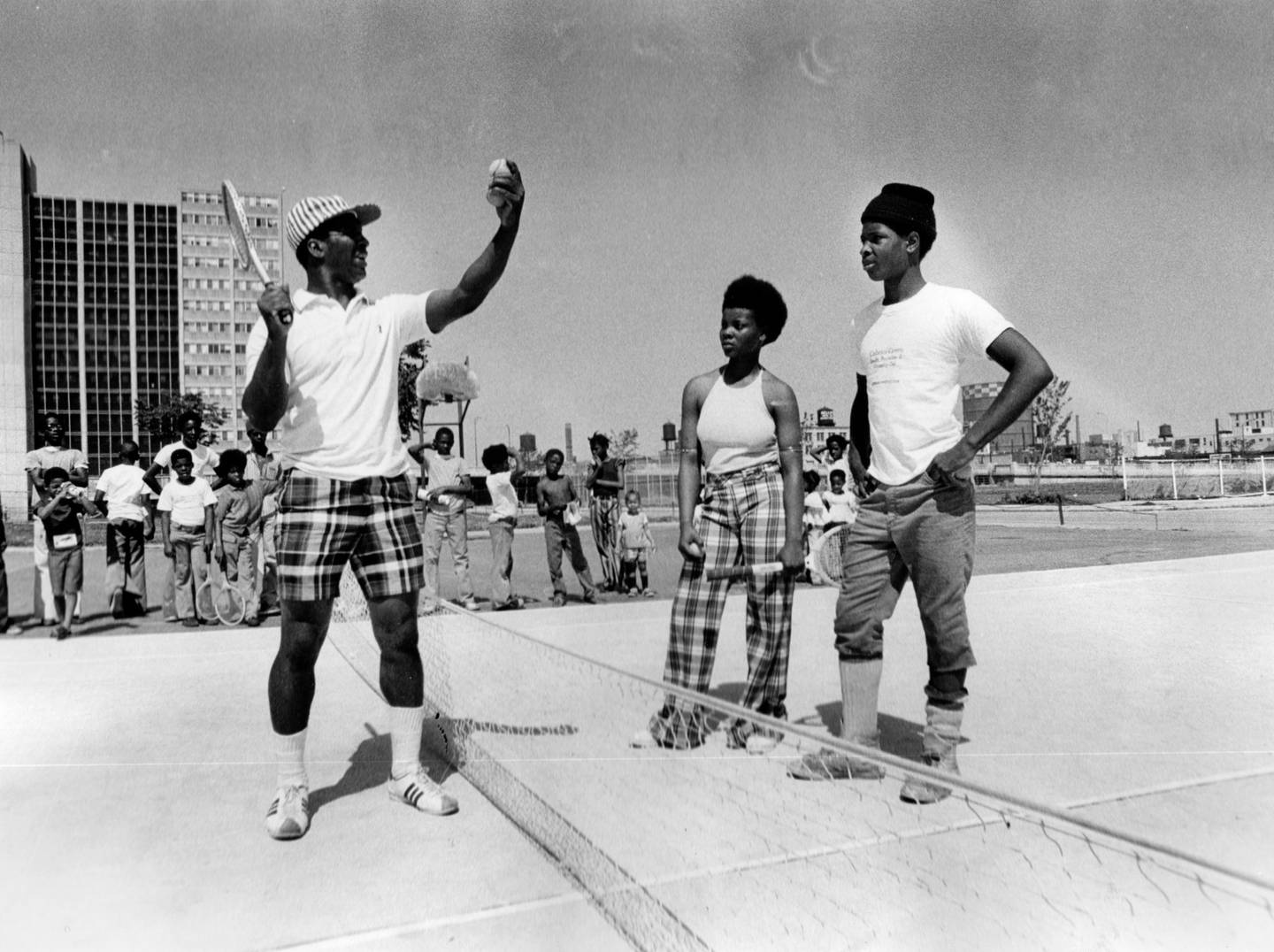 Jesse White, left, tournament director, gives pointers to Cabrini-Green tennis club members Brenda Phillips and James Buford on the tennis courts next to Schiller Elementary School on July 7, 1973. 