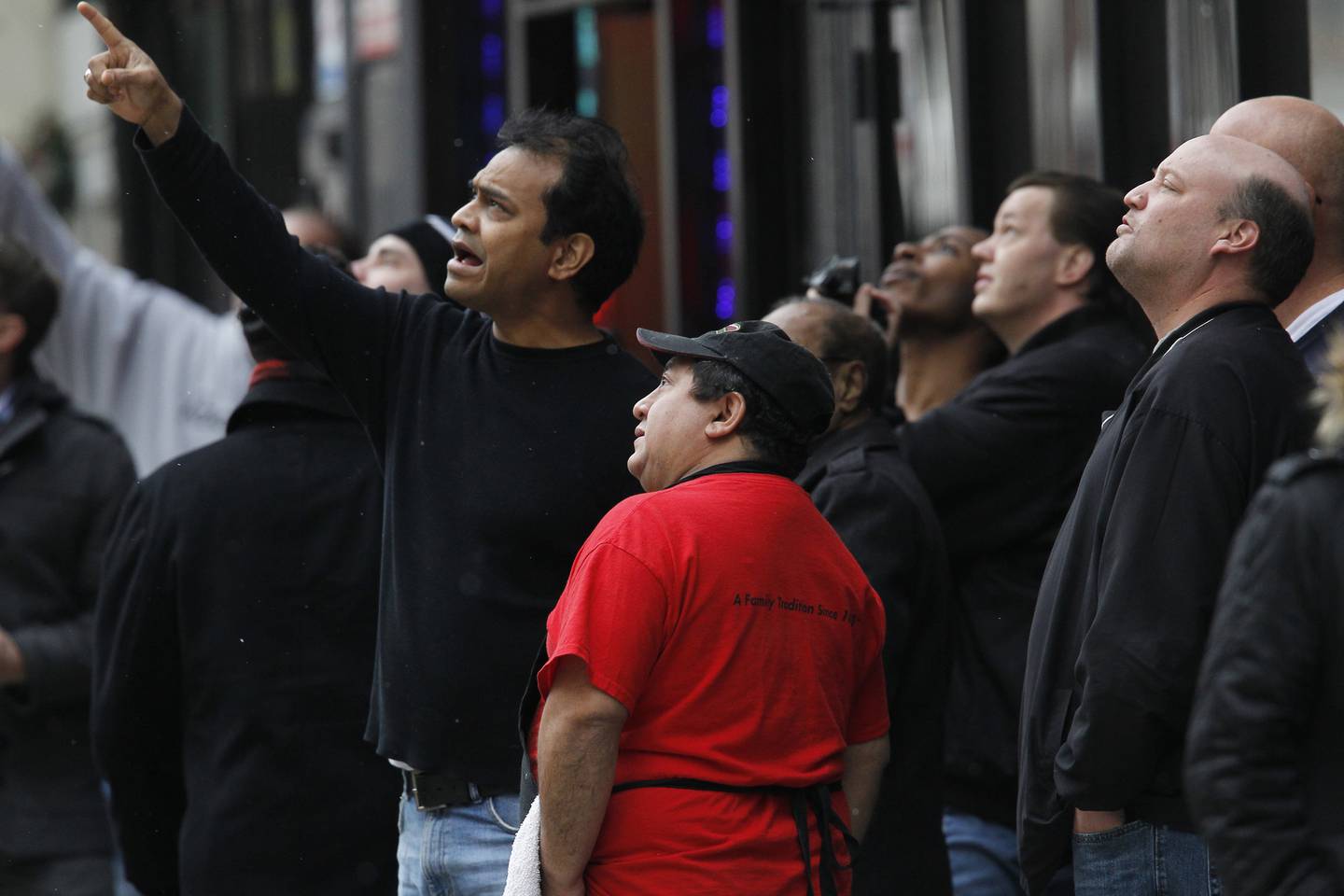 Onlookers, including Aleem Mohammed, pointing, owner of Americana Submarine across from the jail, stop to look at a rope dangling from about 15 stories up along the south side of the Metropolitan Correctional Center.