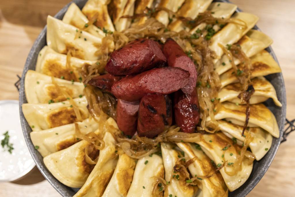 The pan-seared pierogi are served with caramelized onions, charred Polish sausage and fresh-chive sour cream. 