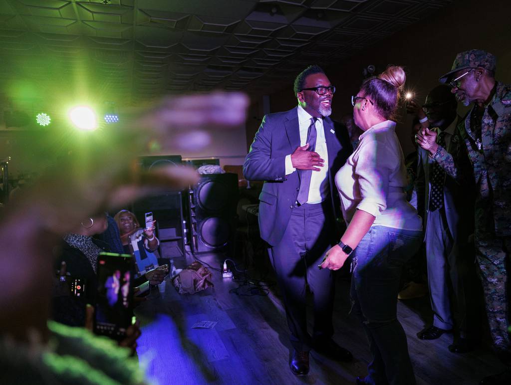 Mayoral candidate Brandon Johnson dances on stage with Lisa Alexander after speaking during a steppers' party in the West Pullman neighborhood on March 29, 2023.