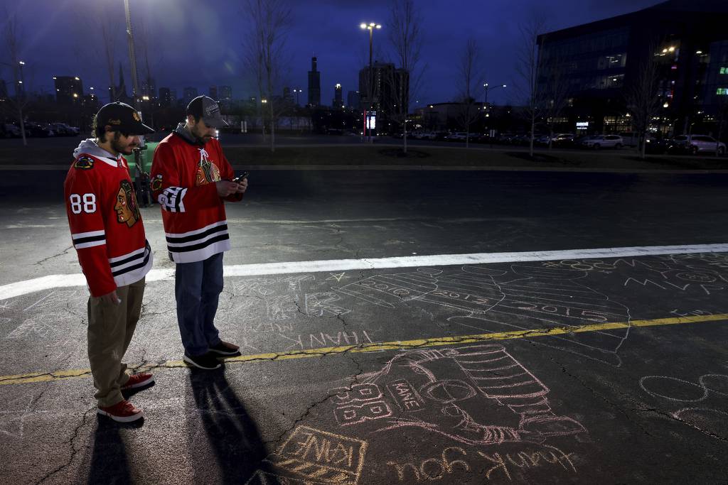 Yehudah David, left, and Ben Abraham, both of Chicago, look at chalk messages in a United Center parking lot honoring former Blackhawks player Patrick Kane on Thursday. Kane was traded to the Rangers on Tuesday.