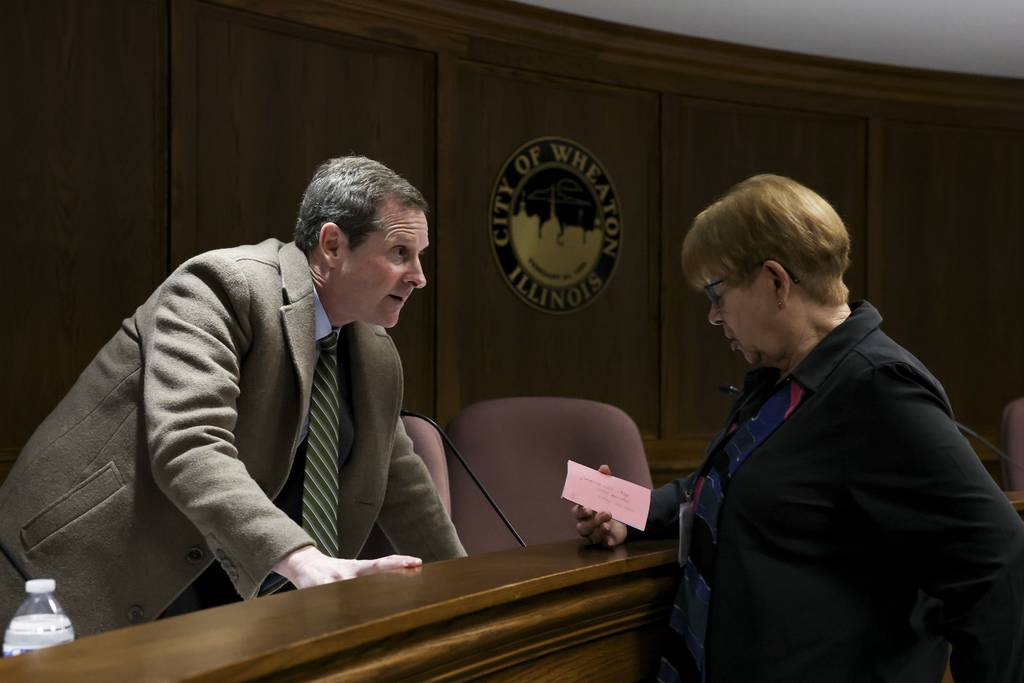 District 200 school board candidate Spencer Garrett talks to a resident after a candidate forum on March. 2, 2023, at City Hall in Wheaton.