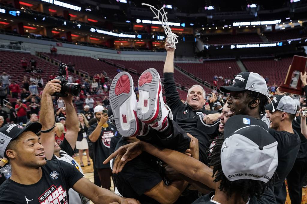 San Diego State coach Brian Dutcher holds the remains of the net and is hoisted in the air by his team after advancing to the Final Four on March 26, 2023.
