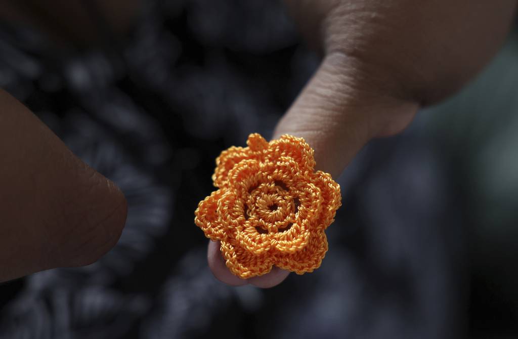 Artist Monserrat Moran holds a crocheted flower that will become an earring decoration, March 21, 2023.