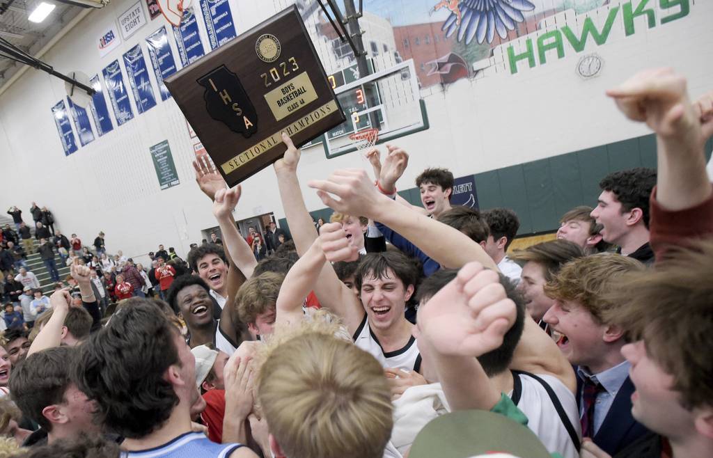 Benet’s Brady Kunka (3) holds up the Class 4A Bartlett Sectional championship trophy as students rush the court to celebrate the 35-34 victory against Geneva on Friday, March 3, 2023. 