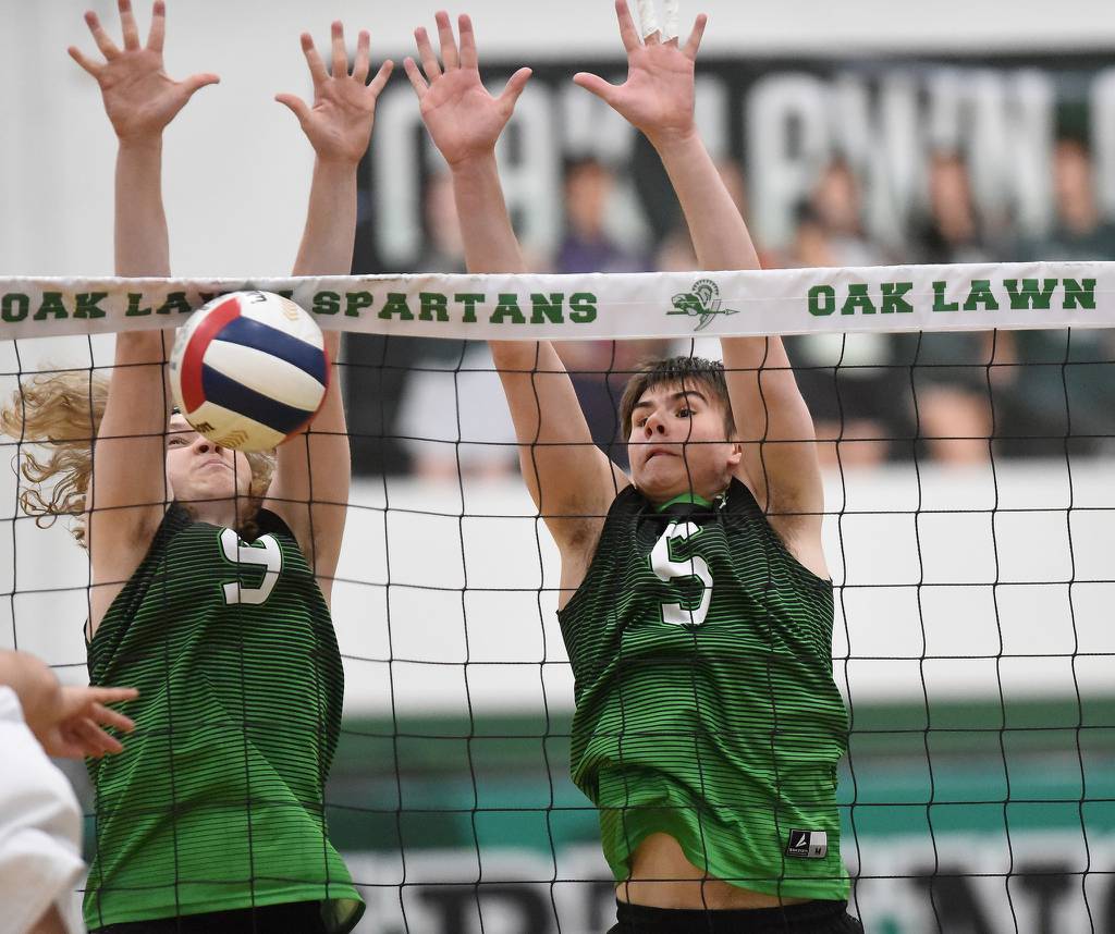 Oak Lawn's Marco Budzak (9) and Connor Lewis (5) go up for a block against St. Laurence during a nonconference match in Oak Lawn on Thursday, March 23, 2023.