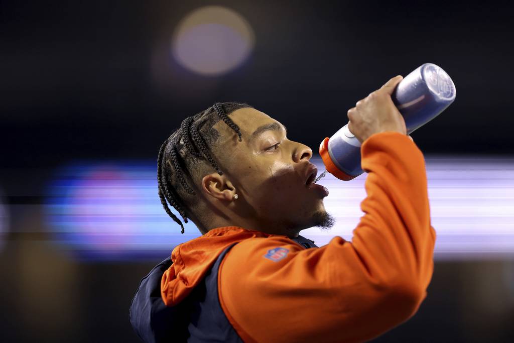 Bears quarterback Justin Fields hydrates during warmups for a game against the Lions on Jan. 1, 2023, in Detroit.