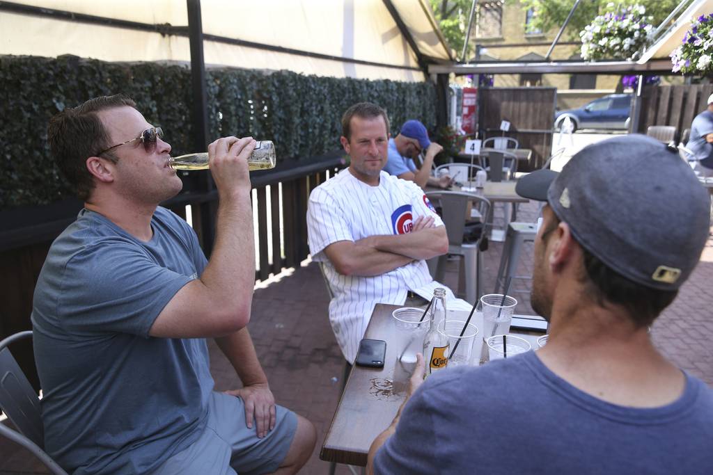 Bill Dwoinen, from left, Chad Edmunds and Tim Drews hang out in the outdoor section of Bernie's Tap and Grill on Clark Street in Chicago's Wrigleyville neighborhood on July 2, 2020. 