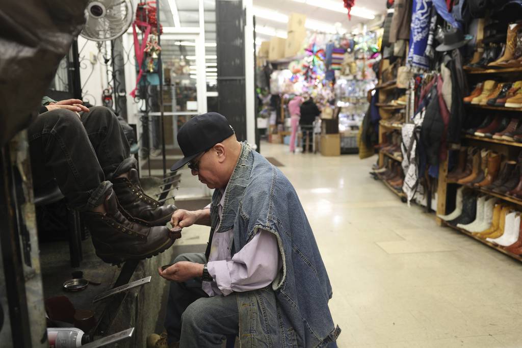 Mario Santos-Mendez shines a man's boots inside the Discount Mall in the Little Village neighborhood on Jan. 5, 2023, in Chicago. 