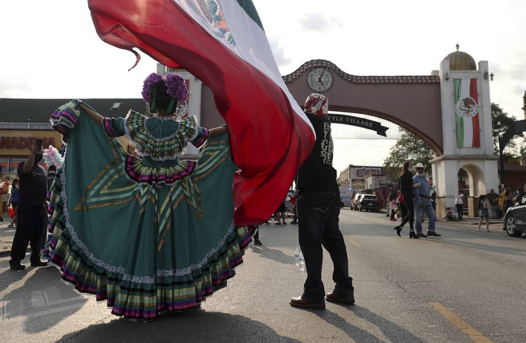 Daniel Ramirez, of Cincinnati, Ohio, holds a Mexican flag as a woman in traditional dress poses for photographs near the Little Village arch during Mexican Independence Day on Sept. 16, 2020, in Chicago. 