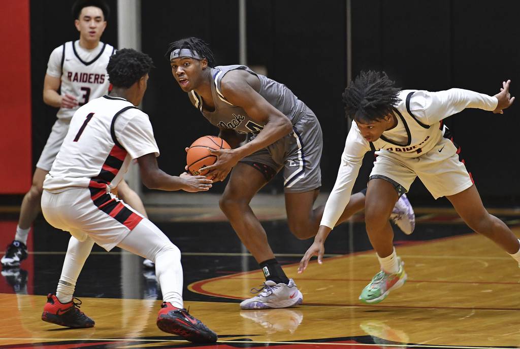 Oswego East's Mekhi Lowery, middle, scoops up a loose ball while surrounded by Bolingbrook players during a Class 4A Bolingbrook Sectional semifinal game on Wednesday, March 1, 2023.
