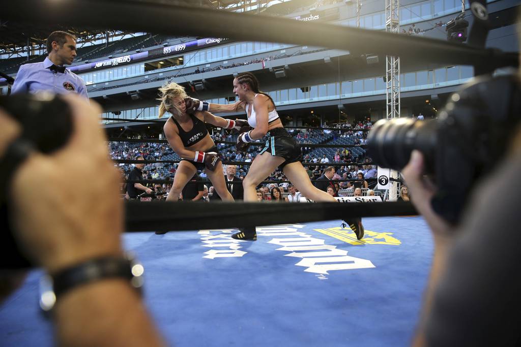 Amanda Cooper takes a punch from Kristin Gearhart in the fourth round of their fight during the Friday Night Fights event at U.S. Cellular Field in Chicago on Aug. 16, 2013.  