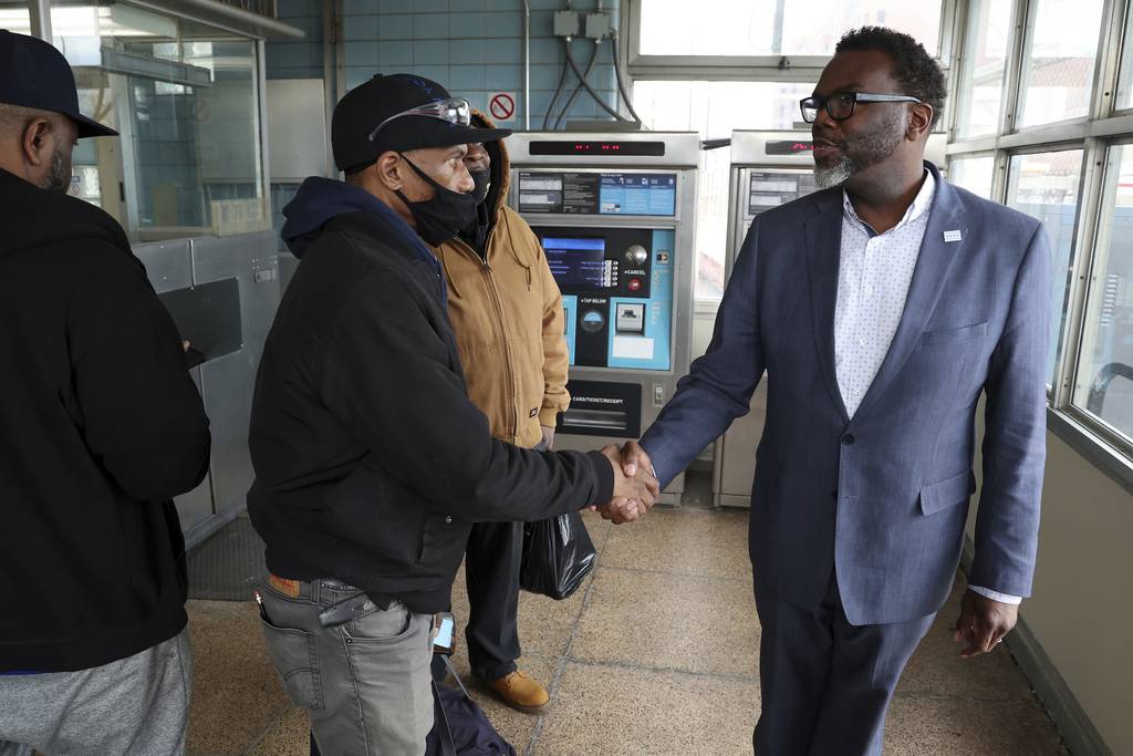 Chicago mayoral candidate Brandon Johnson, right, greets commuter Edison Edwards at the Racine Avenue CTA Blue Line Station while campaigning on April 3, 2023. 
