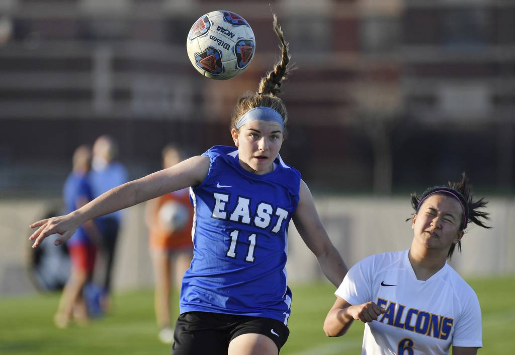 Lincoln-Way East's Cami Butler (11) heads the ball away from Wheaton North’s Lauren Nguyen during the Porter Cup championship game in Lockport on Thursday, April 13, 2023.