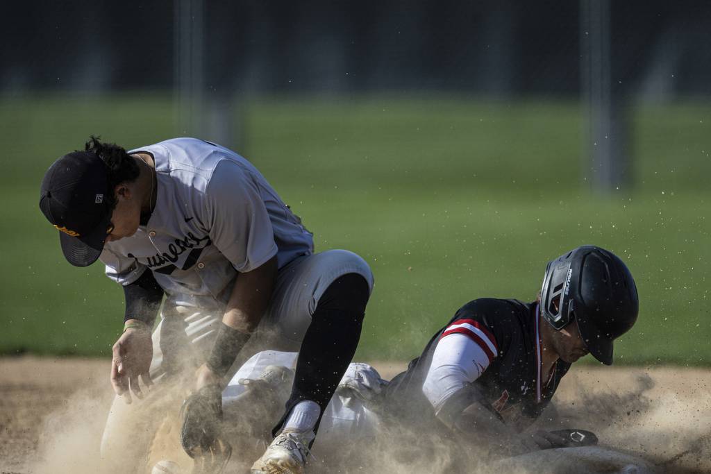 Marist’s Jack Wade (12) dives back to first base on a pickoff attempt as St. Laurence's Michael Carrano (27) fields the ball during a nonconference game in Chicago on Tuesday, April 18, 2023.
