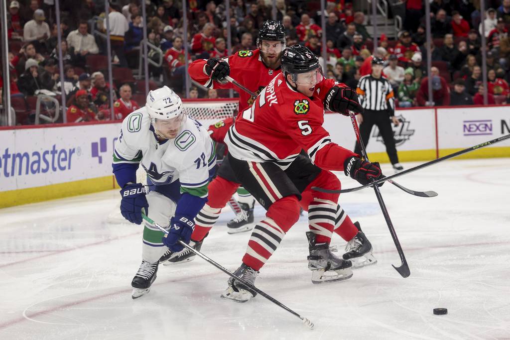 Blackhawks defenseman Connor Murphy passes the puck by while being guarded by Canucks left wing Anthony Beauvillier during the second period on March 26 at the United Center. 