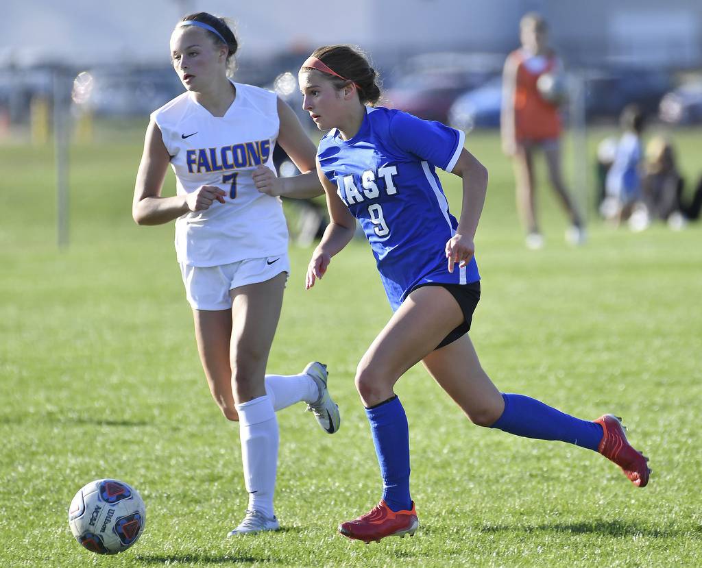 Lincoln-Way East's Elizabeth Burfeind (9) moves the ball ahead of Wheaton North’s Calah Strong during the Porter Cup championship game in Lockport on Thursday, April 13, 2023.