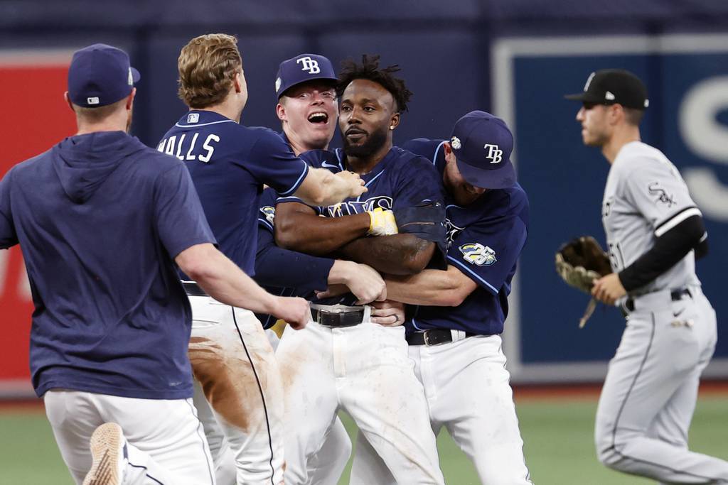 Rays left fielder Randy Arozarena, center, is embraced by Pete Fairbanks, left and Luke Raley after hitting a game-winning RBI single against the White Sox in the 10th inning Saturday in St. Petersburg, Fla. 