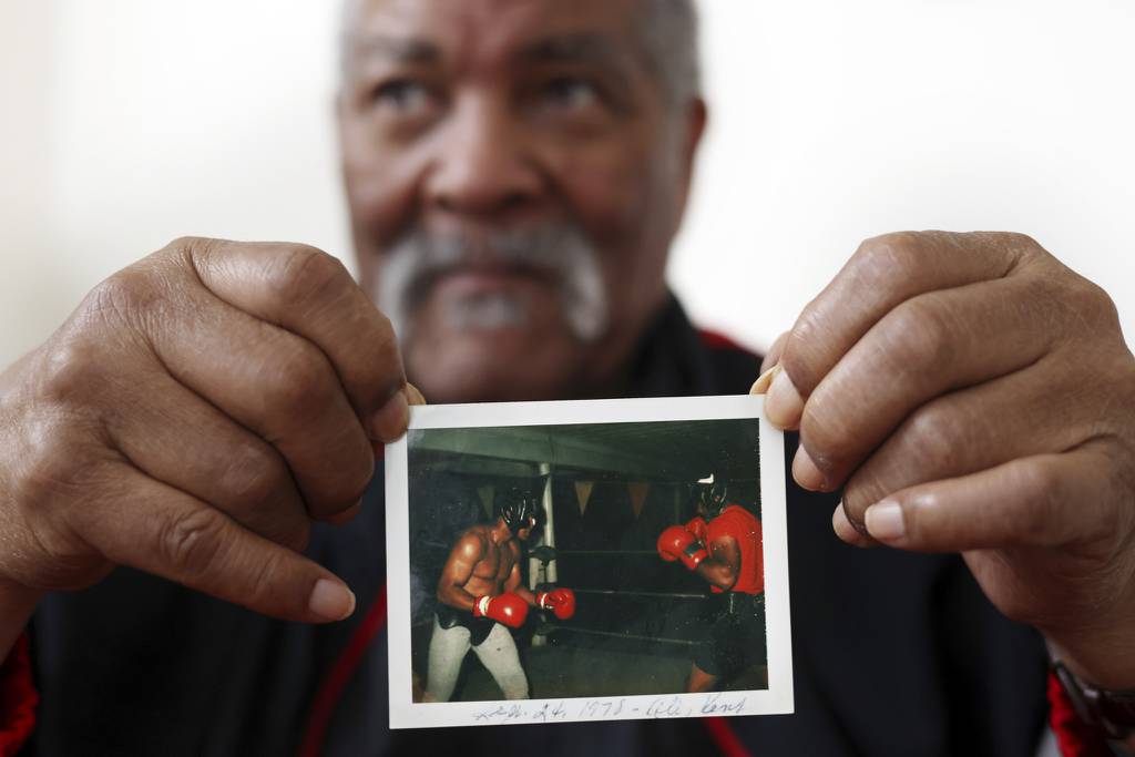 Kent Greene, 83, holds a 1978 polaroid photo of himself, right, sparring with Muhammad Ali. Greene defeated Ali in the 1958 Chicago Golden Gloves. 