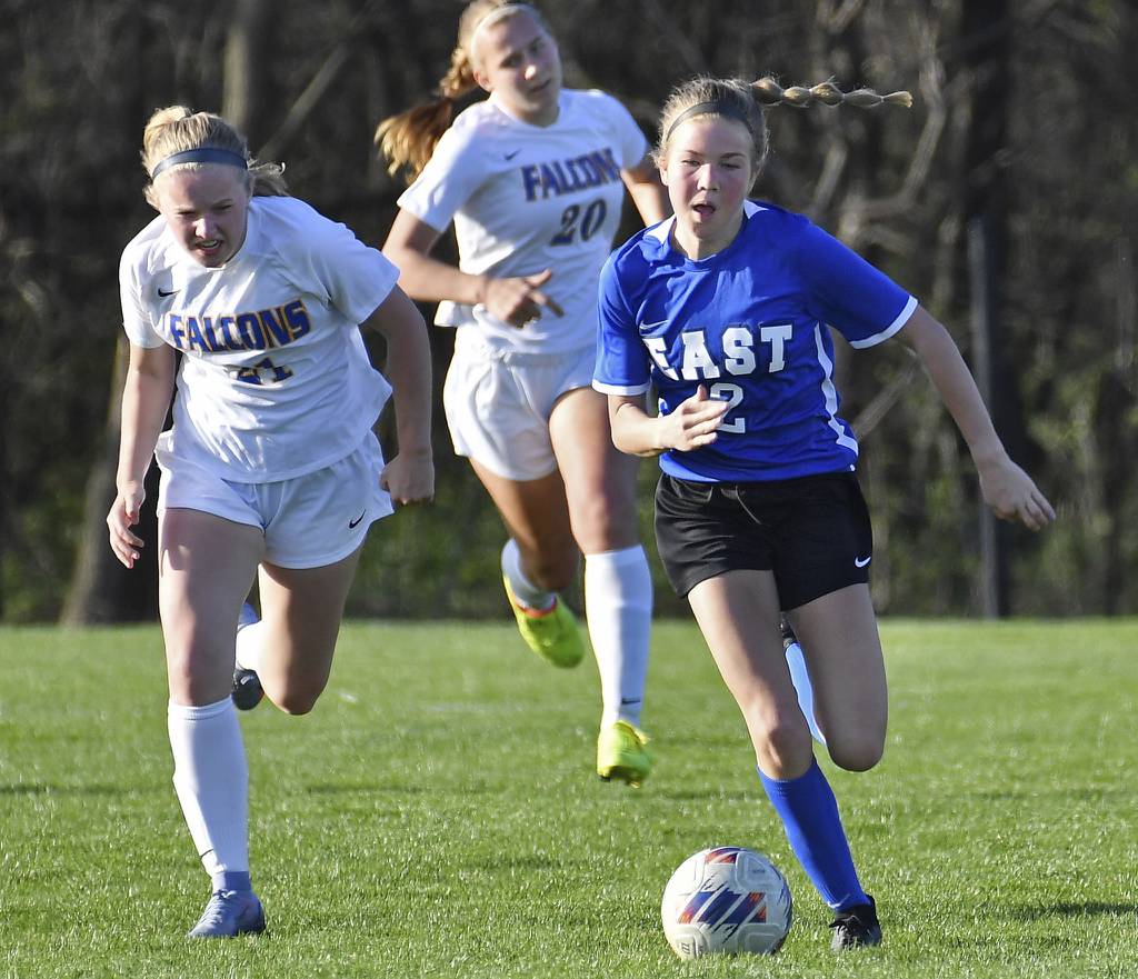 Lincoln-Way East's Kara Waishwell, right, races with the ball ahead of two Wheaton North defenders during the Porter Cup championship game in Lockport on Thursday, April 13, 2023.