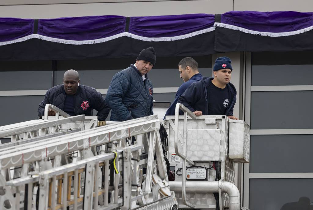 Chicago Fire Department members drape memorial bunting over the engine house on West 119th Street where firefighter Jermaine Pelt worked after Pelt died, April 4, 2023.