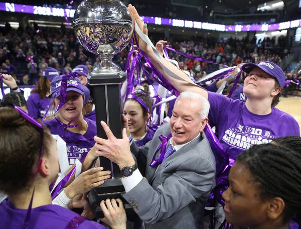 Northwestern's Abbie Wolf, right, touches the Big Ten Conference championship trophy as it is held by coach Joe McKeown after beating Illinois on Feb. 29, 2020.