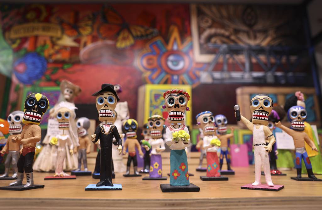Day of the Dead figurines are on display beside the “México del Norte” mural by artist Robert Valadez at Colores Mexicanos.