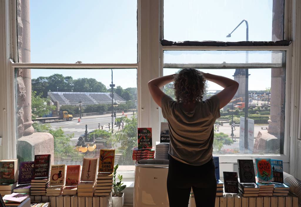 Kristin Enola Gilbert, co-owner of Exile in Bookville bookstore, looks from the store's windows at NASCAR Chicago Street Race construction in the 400 block of South Michigan Avenue, June 24, 2023.