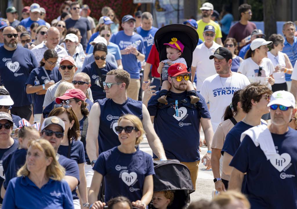 Highland Park community members walk along Central Avenue through downtown, July 4, 2023, to mark the one-year anniversary of last year’s mass shooting.