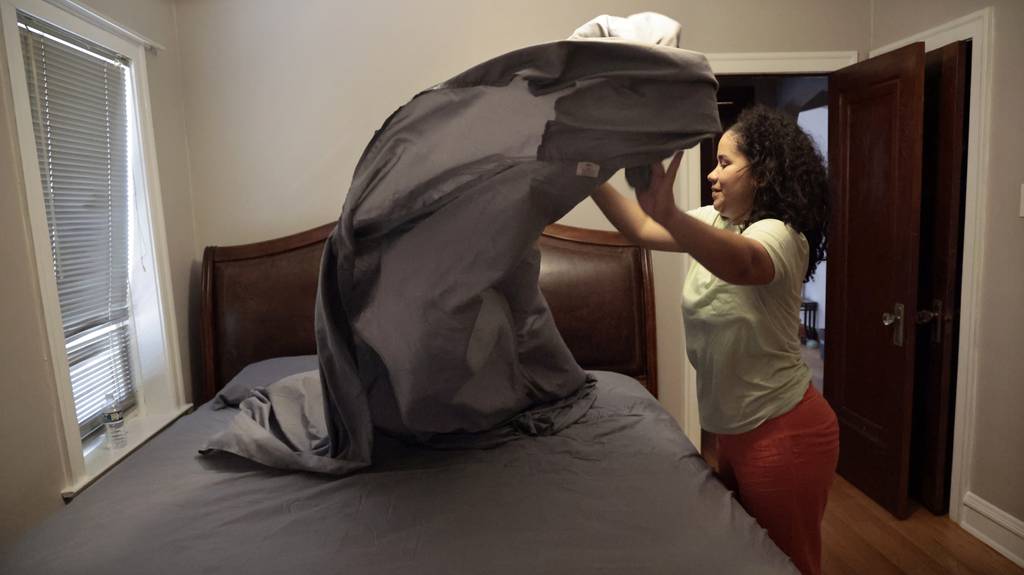 Venezuelan migrant Ari makes the bed in her Chicago apartment.