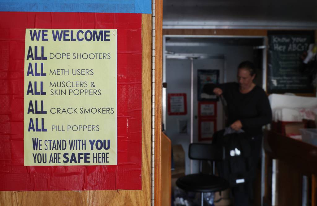 A sign about helping drug users regardless of their addiction is posted on a wall in a mobile outreach van as Karen Bigg, a harm reductionist for the Chicago Recovery Alliance, prepares a backpack of items for a user at Humboldt Park on July 25, 2023, in Chicago. 