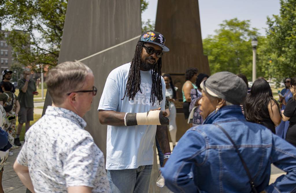 Shermann “Dilla” Thomas talks to people at the Ida B. Wells monument during a Mahogany Bus Tour of Bronzeville on June 18, 2023.