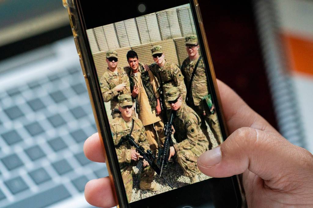 Romal shows a picture on his phone from his time working with U.S. troops in Afghanistan on June 26, 2023.