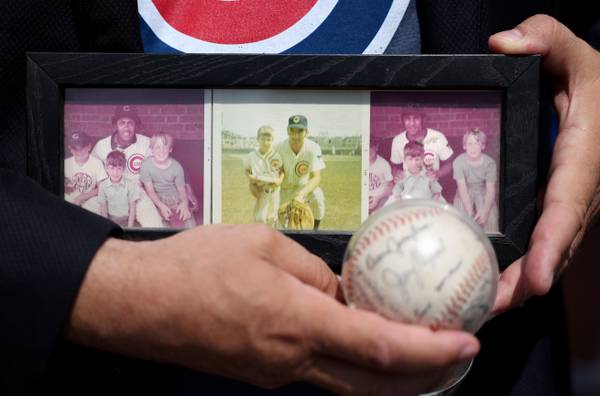 Sam Fazio holds framed photographs from the early 1970’s featuring him as a batboy with Cubs players Fergie Jenkins, Ron Santo, and Billy Williams.
