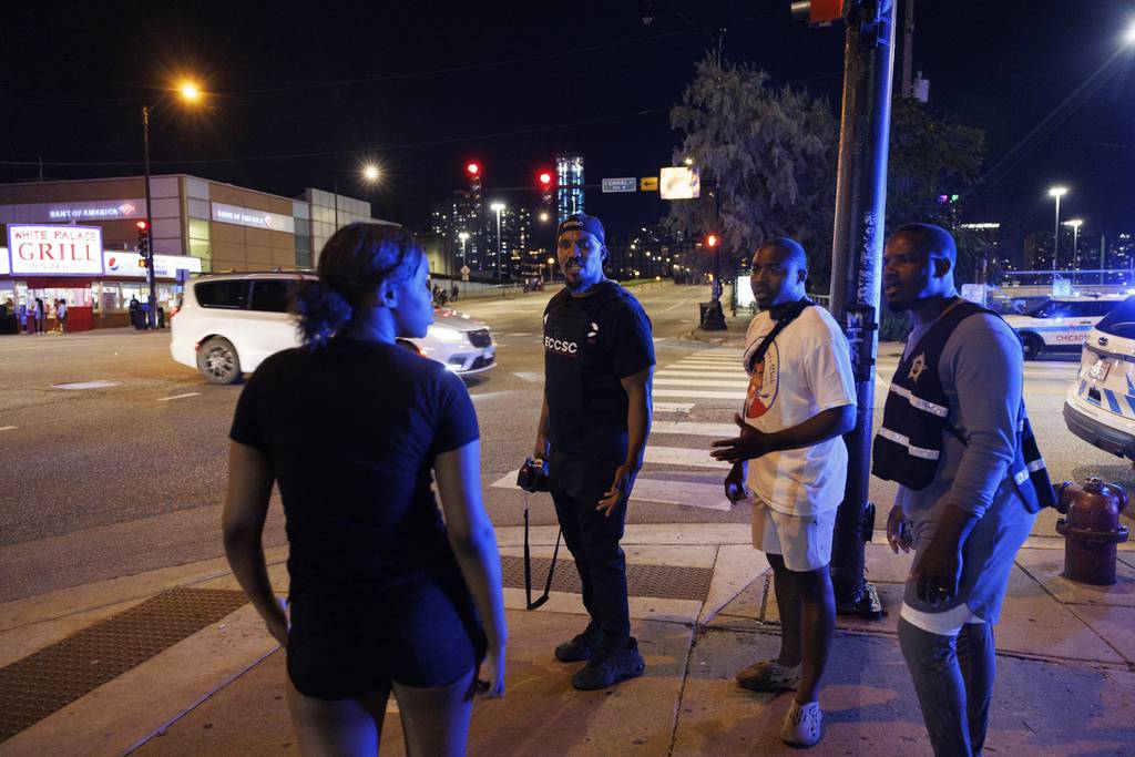From right, Charles McKenzie, of Englewood First Responders, Joseph Williams, of Mr. Dad’s Father’s Club, and Tyrone Muhammad of Ex-Cons for Community and Social Change, talk with a young person while trying to help officers disperse a large group of young people gathered near the intersection of South Canal Street and West Roosevelt Road.