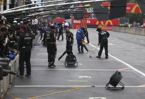 Crew members clear the water from pit road after the NASCAR Cup Series was delayed due to rain in Chicago on July 2, 2023.