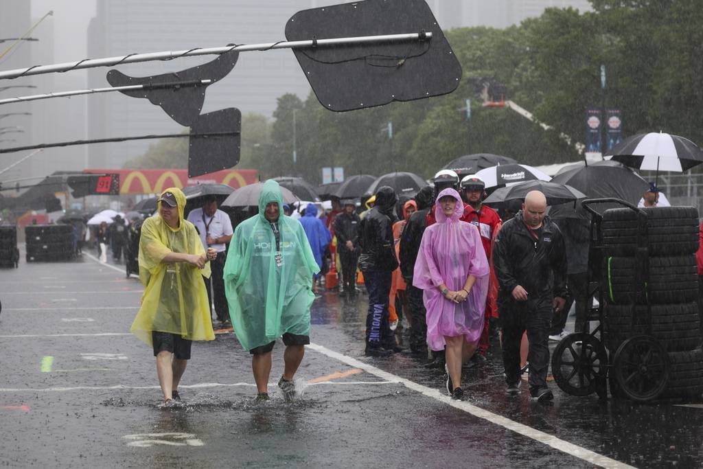 People walk along a flooded pit road on Columbus Drive while the NASCAR Cup Series is delayed due to rain in Chicago on July 2, 2023. 