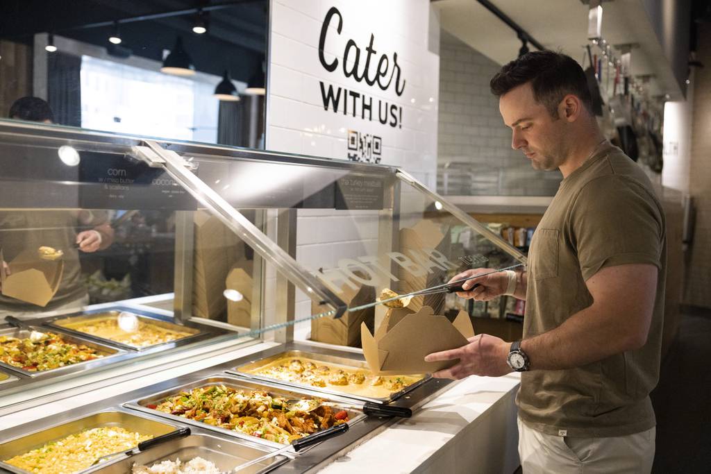 Patrick Dorgan fills up a compostable to-go container at Beatrix Market in the Loop on June 27, 2023.