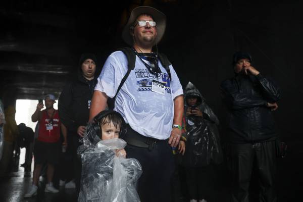 Brandon Eggers, right, and Reagan Eggers wait underneath the Paddock Club bridge along Columbus Drive while the NASCAR Cup Series is delayed due to rain in Grant Park on July 2, 2023.