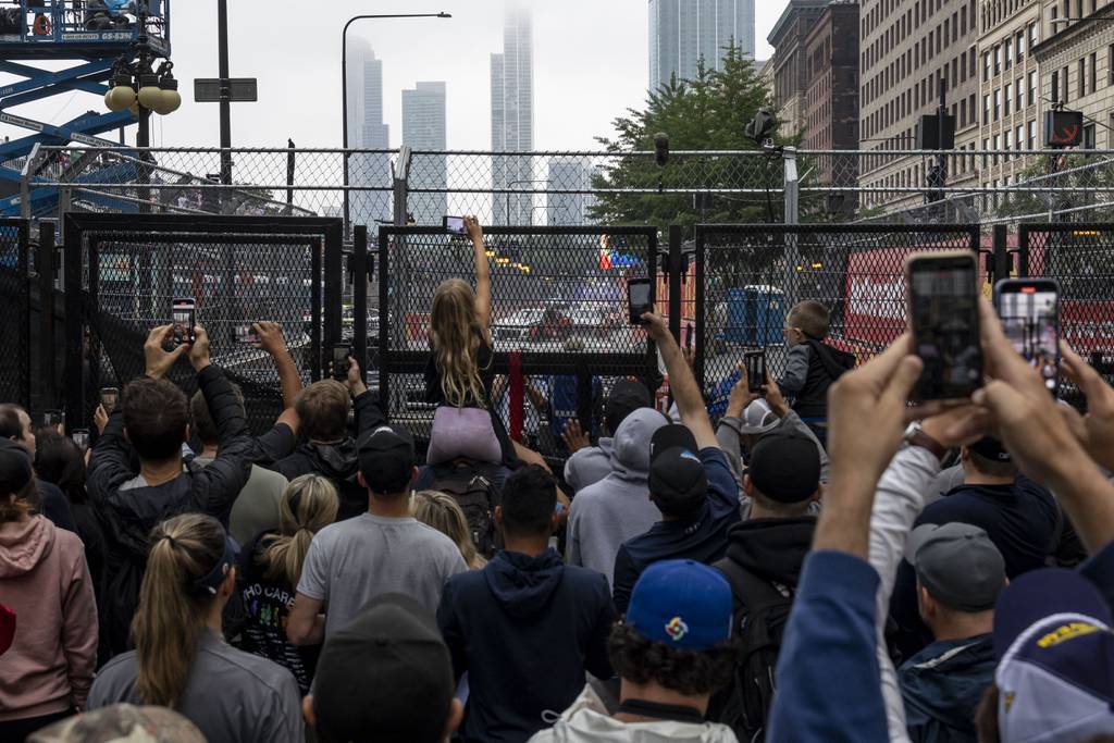 Fans along South Michigan Avenue try to catch a glimpse of the action after they tear down a tarp blocking the view as the NASCAR Cup Series race gets underway on July 2, 2023.