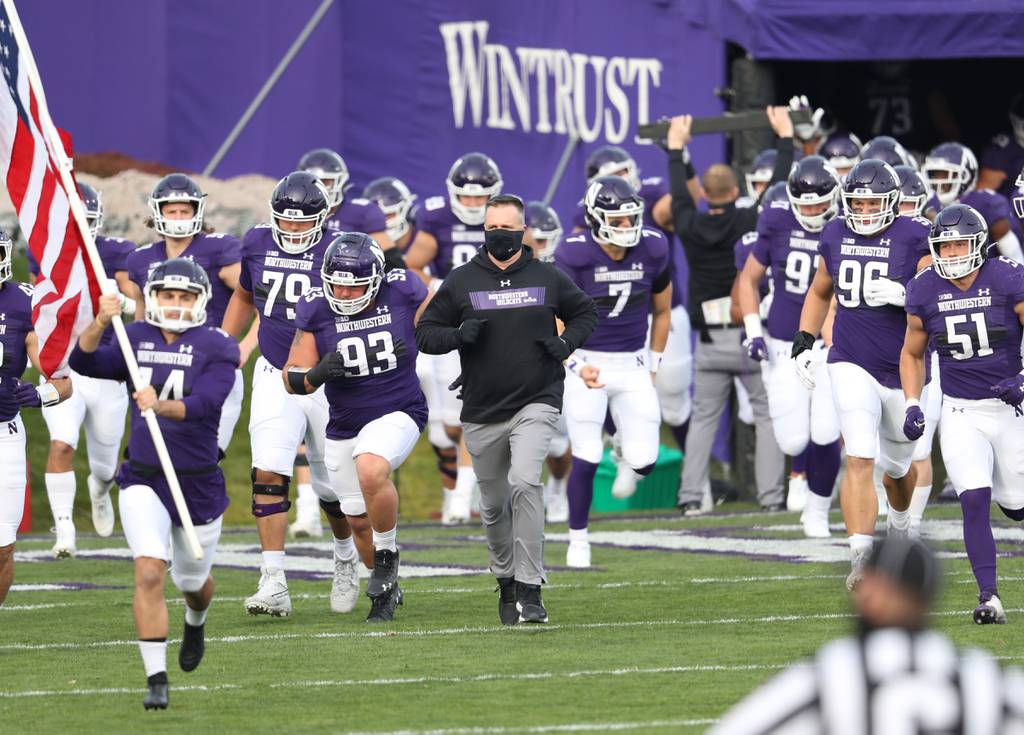 Northwestern Wildcats head coach Pat Fitzgerald, center, enters the field with his team for a game against the Wisconsin Badgers at Ryan Field on Nov. 21, 2020, in Evanston. Fitzgerald was fired Monday “for his failure to know and prevent significant hazing in the football program,” according to a university statement.