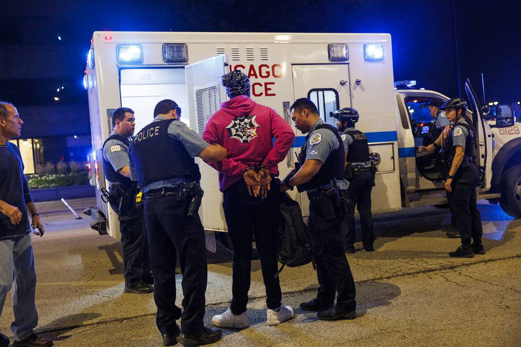 Officers detain a person as police attempt to disperse a large group of young people gathered near the intersection of South Canal Street and West Roosevelt Road on July 30, 2023.