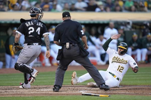 Athletics' Aledmys Díaz scores next to White Sox catcher Yasmani Grandal on Jace Peterson's sacrifice fly during the second inning on June 30, 2023.