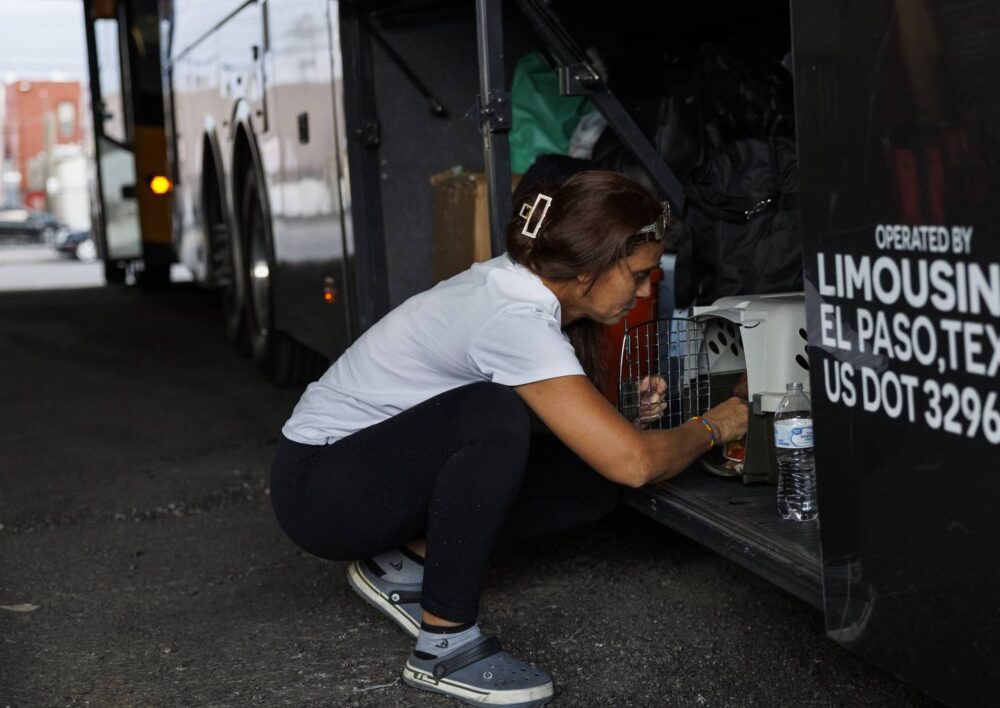 Esperanza gives Milo the dog water after learning he’ll have to sit with the luggage under the bus for the 11-hour ride to Denver on July 13, 2023, in El Paso, Texas. 
