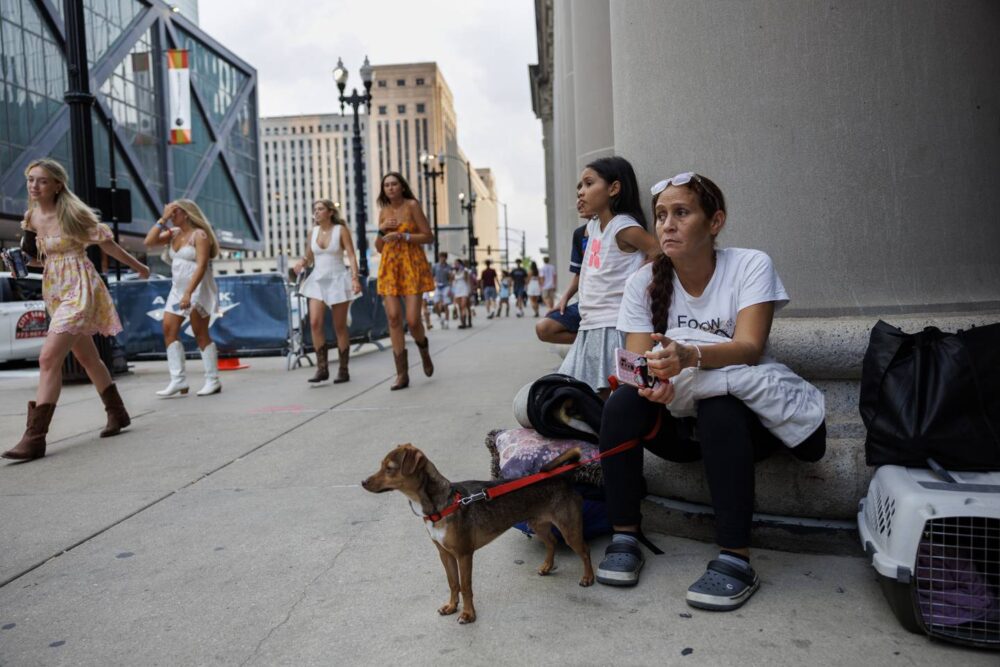 Esperanza holds onto Milo as a group of people walk past the family as they wait outside Union Station after riding a train for 18 hours to get to Chicago on July 15, 2023. After arriving at Union Station, no city officials or volunteers were present to assist the family in finding shelter.