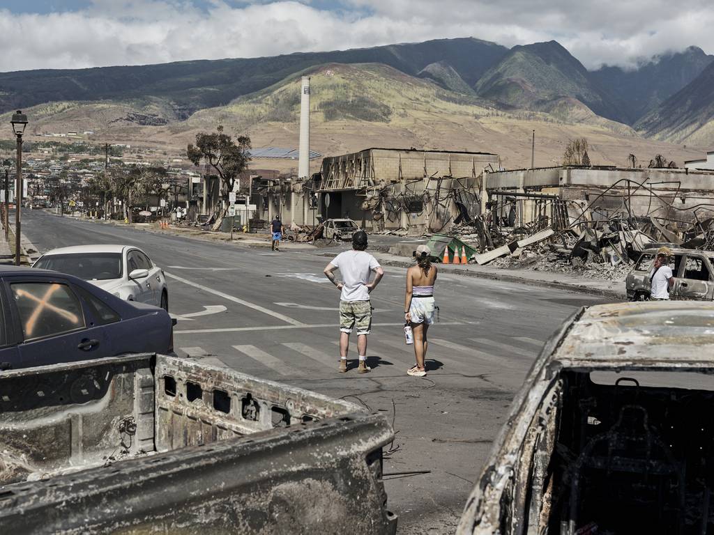 People surveying wildfire damage in Lahaina, Hawaii, on Aug. 11, 2023. During the last half-century, the town on the island of Maui transformed from a center of agriculture to a tourism magnet. 