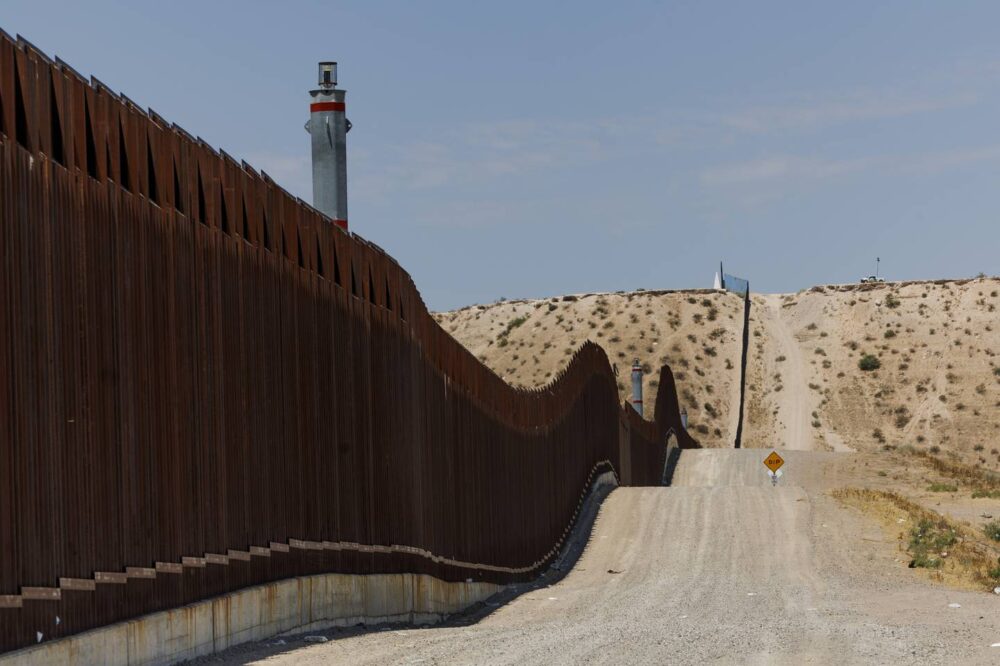 Tall fencing along the U.S.-Mexican border sits near a dirt path on July 9, 2023, in Sunland Park, New Mexico. Members of the U.S. Border Patrol used the path while on duty in the area. 
