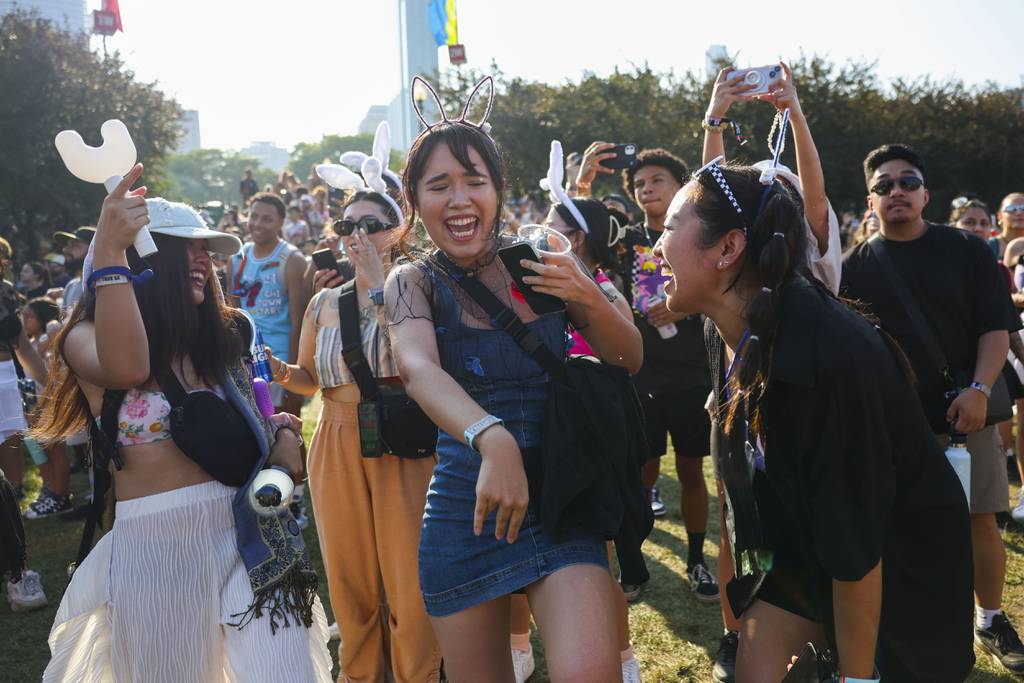 Linda Le, of Oakland, Cal., from left, Brittany Lanham, of Los Angeles, and Abby Comes, of Los Angeles, dance as NewJeans performs at Lollapalooza on Aug. 3, 2023.  