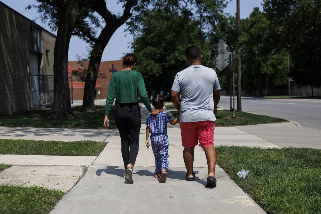 Eliany Pina and her husband, Jonni Cespedes, walk with their daughter, Hassly Cespedes, to Martin Temple AME Zion Church to get food on Aug. 21, 2023, in Chicago. 