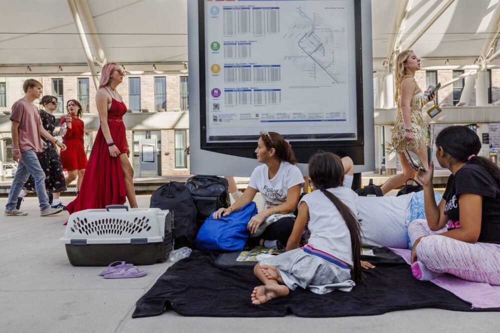 The Mendez family watches as pedestrians pass on their way to the Taylor Swift concert in Denver, while they wait for the train to Chicago on July 14, 2023. “How pretty,” Esperanza said to Yuledy.